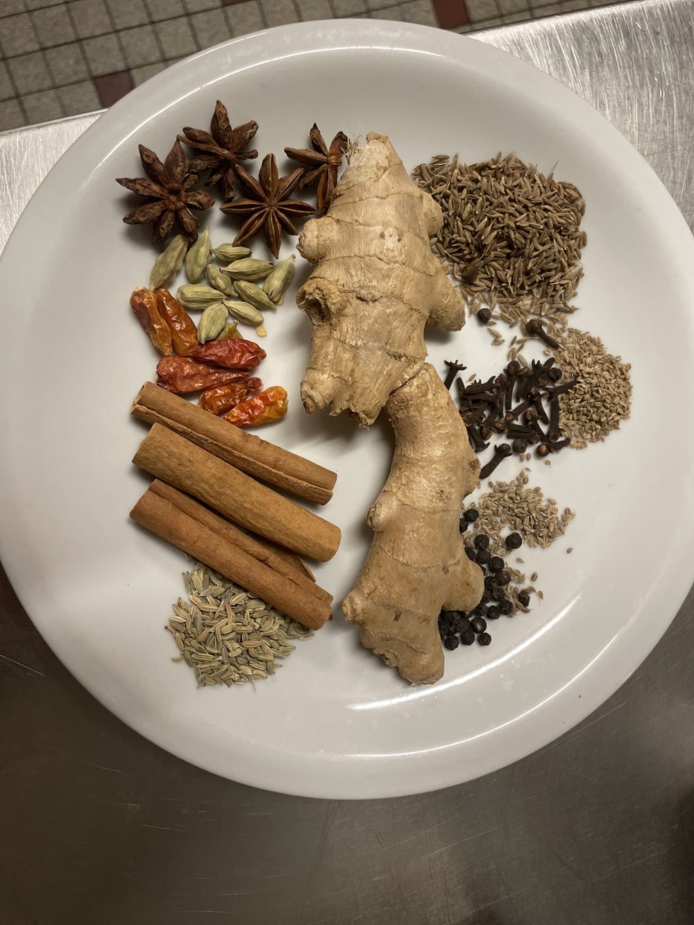 Les épices de Richard sur une assiette : badiane, cardamome, piments, cannelle, gingembre frais, cumin, clous de girofle, poivre